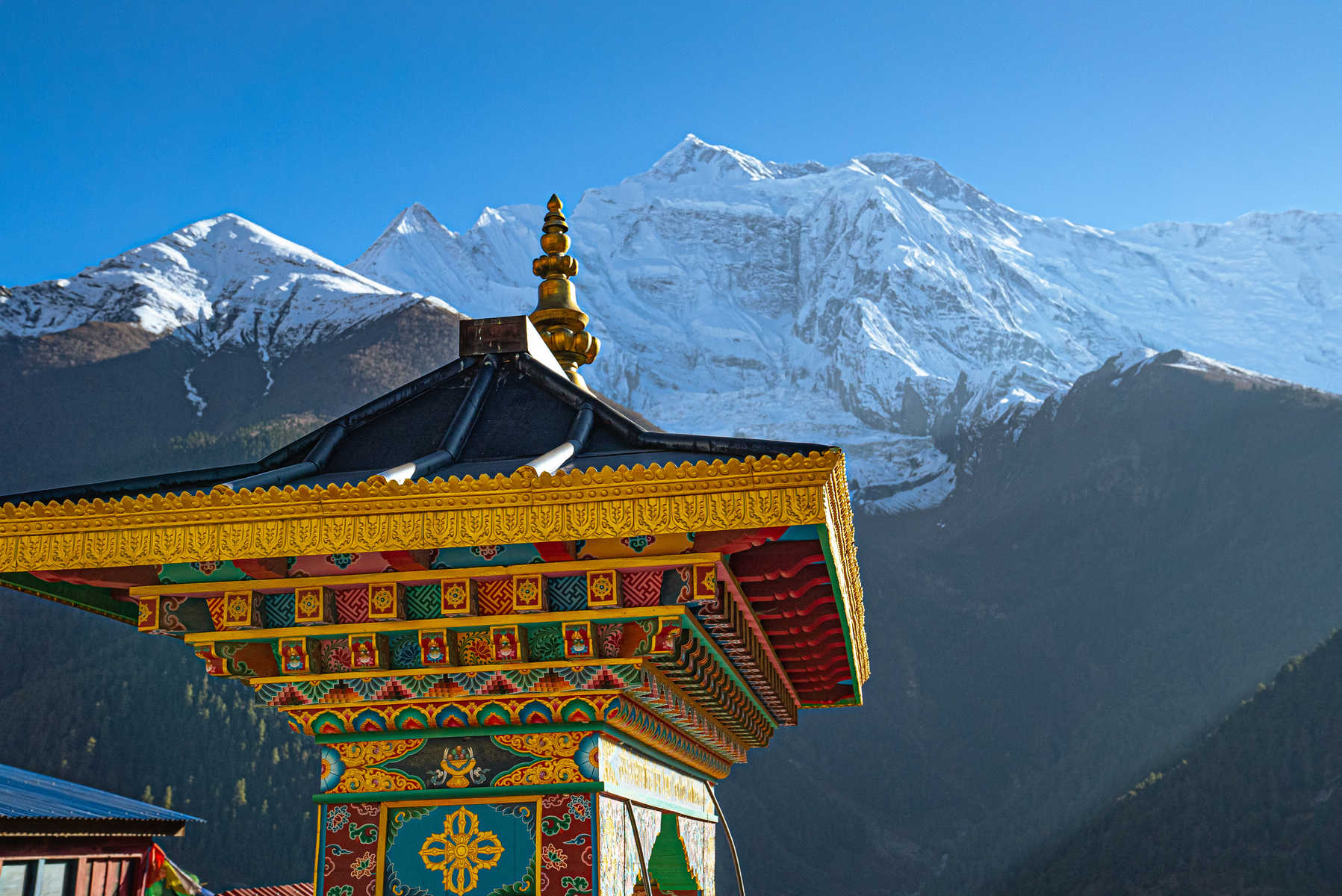Entrée d'un temple coloré avec la chaîne de l'Annapurna au loin, Népal