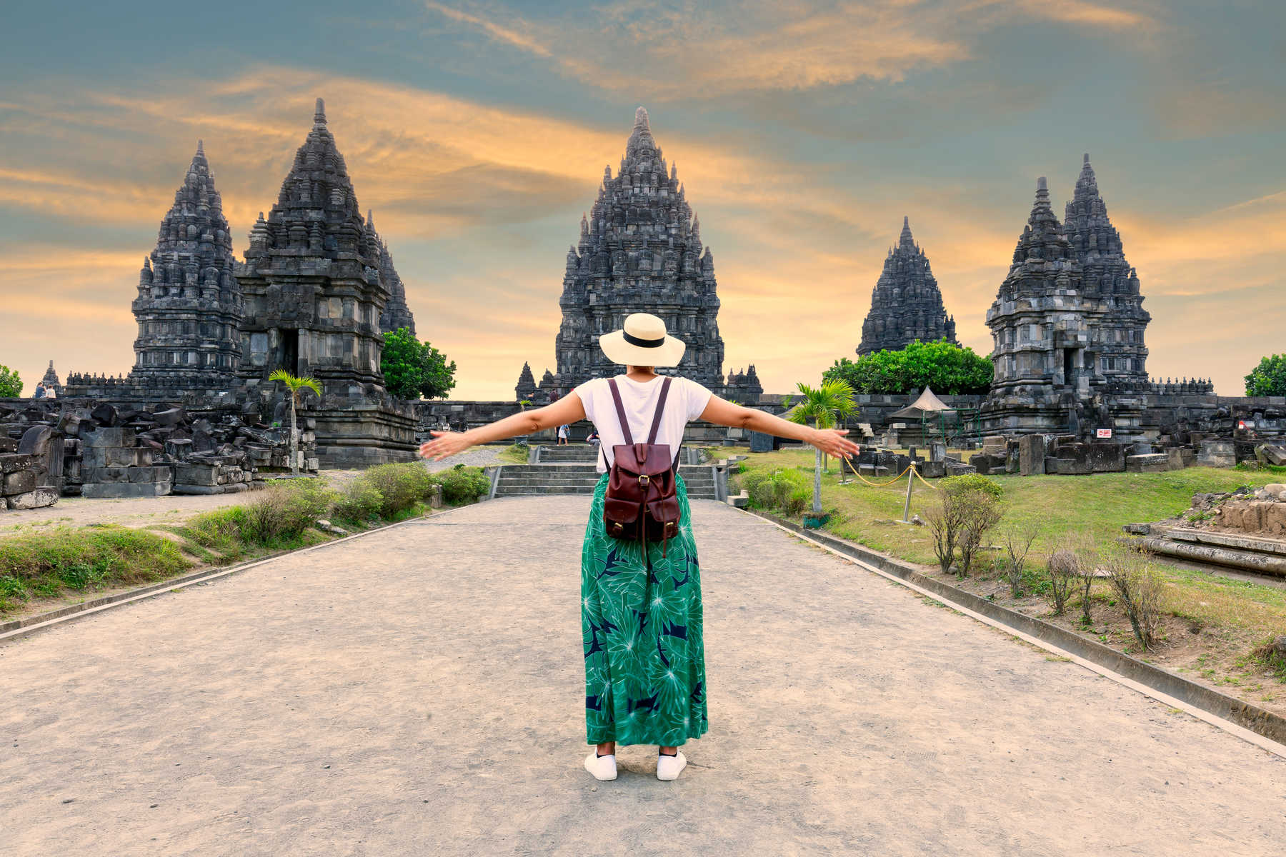 jeune fille avec un chapeau debout à bras ouverts regardant le temple de Prambanan en indonésie