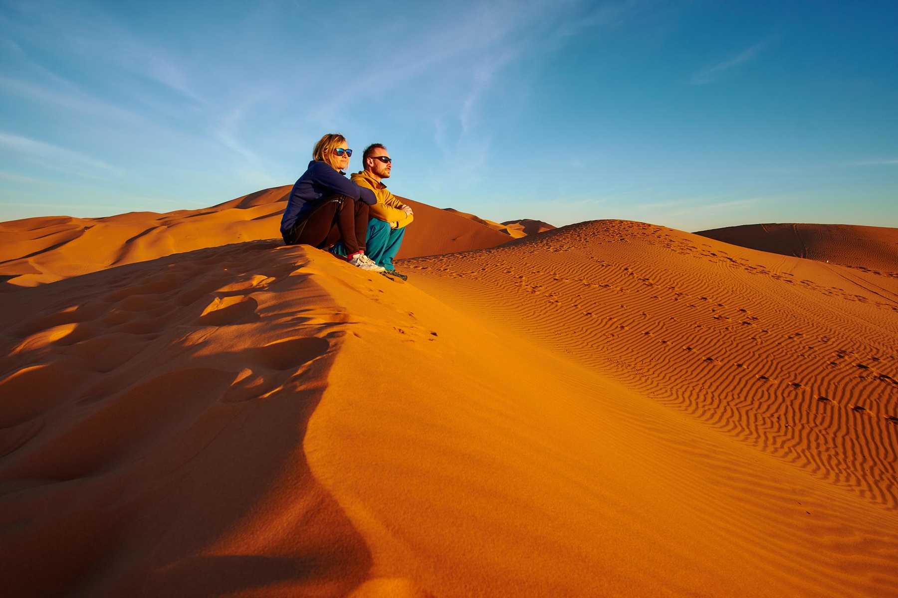 Randonneurs sur les dunes de Merzouga devant un coucher de soleil