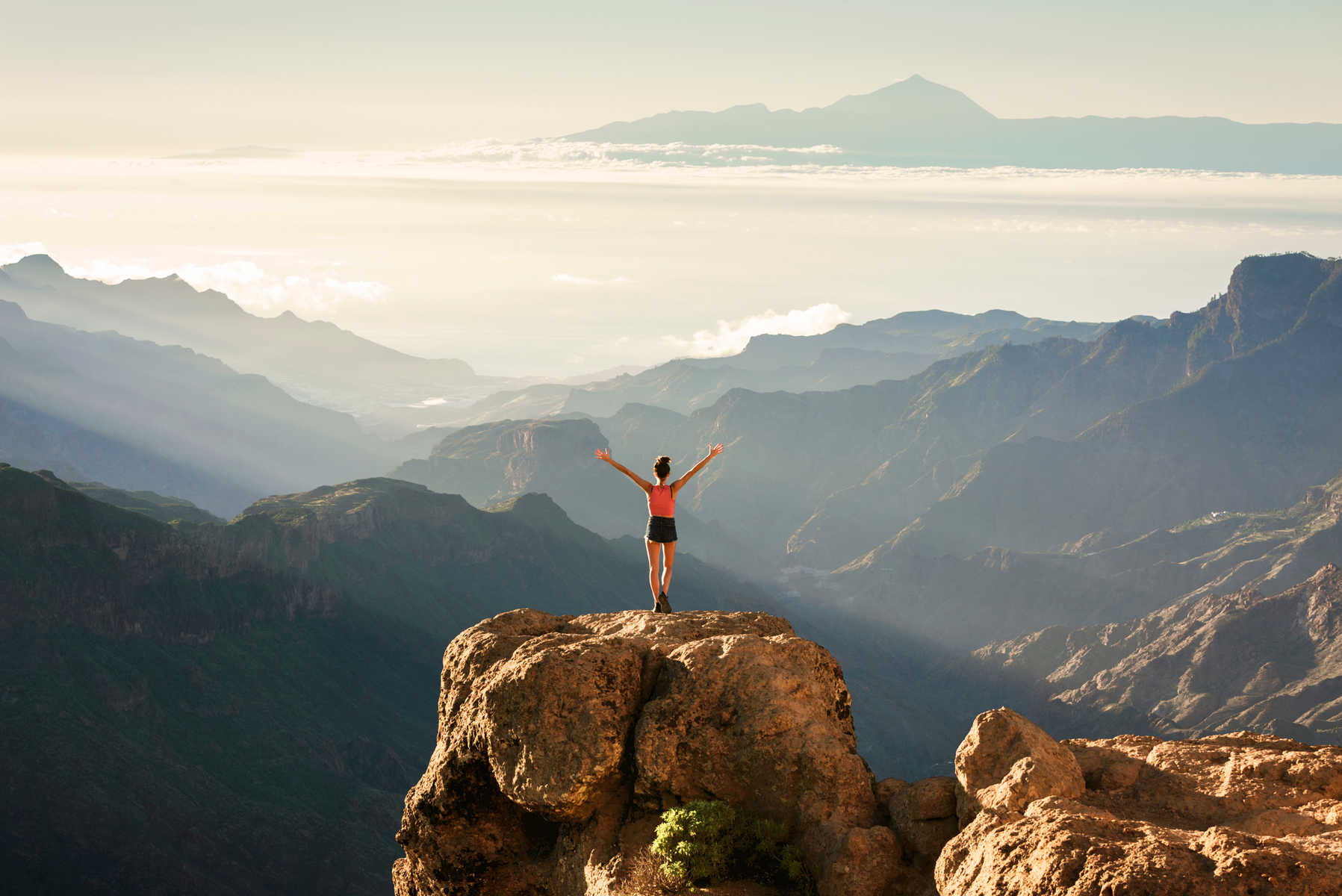 Une femme debout sur un rocher de Gran Canaria et face au Mont Teide