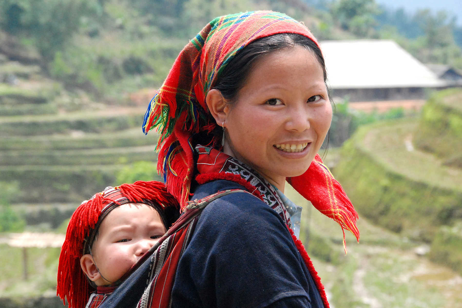 Une femme en costume traditionnel avec son enfant dans le dos au Vietnam