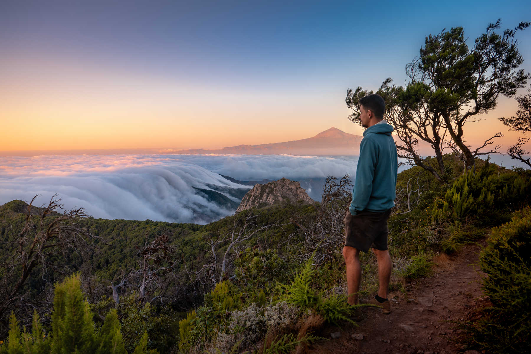 Une personne qui regarde le coucher de soleil depuis le Parc National de Garajonay avec le mont Teide en fond