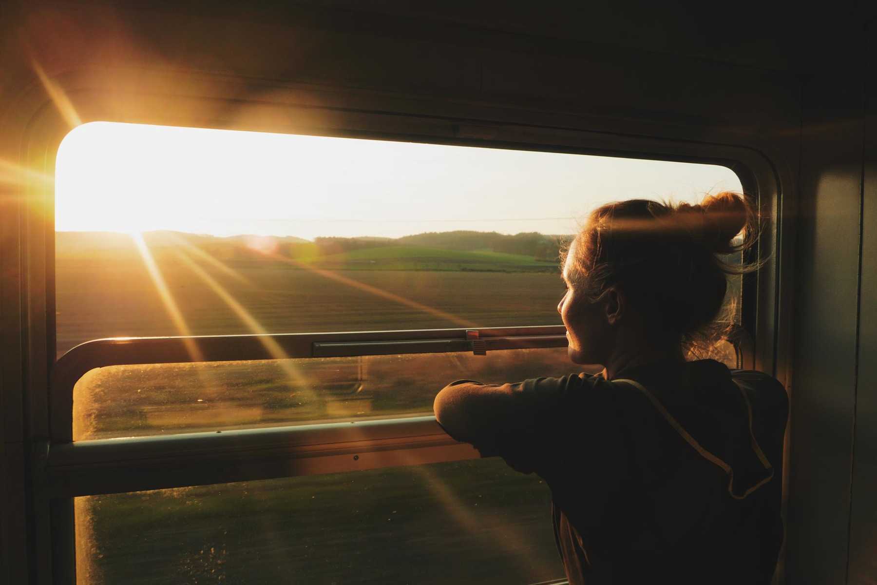 Voyageuse en train face aux lumières du soir