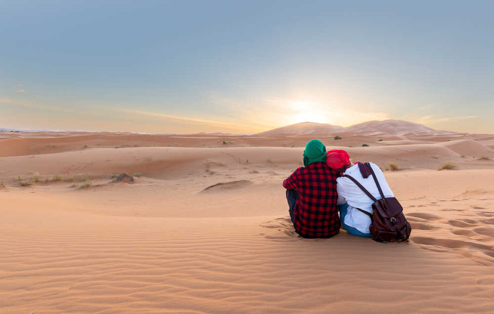 Couple de voyageurs profitant de la vue sur le désert de Merzouga, Maroc