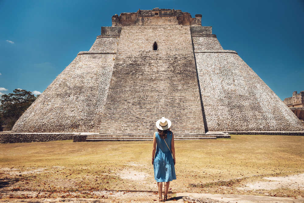 Femme de dos observant la pyramide de Uxmal au Mexique