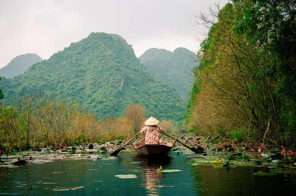 Femme locale sur une pirogue au milieu des montagnes, Vietnam
