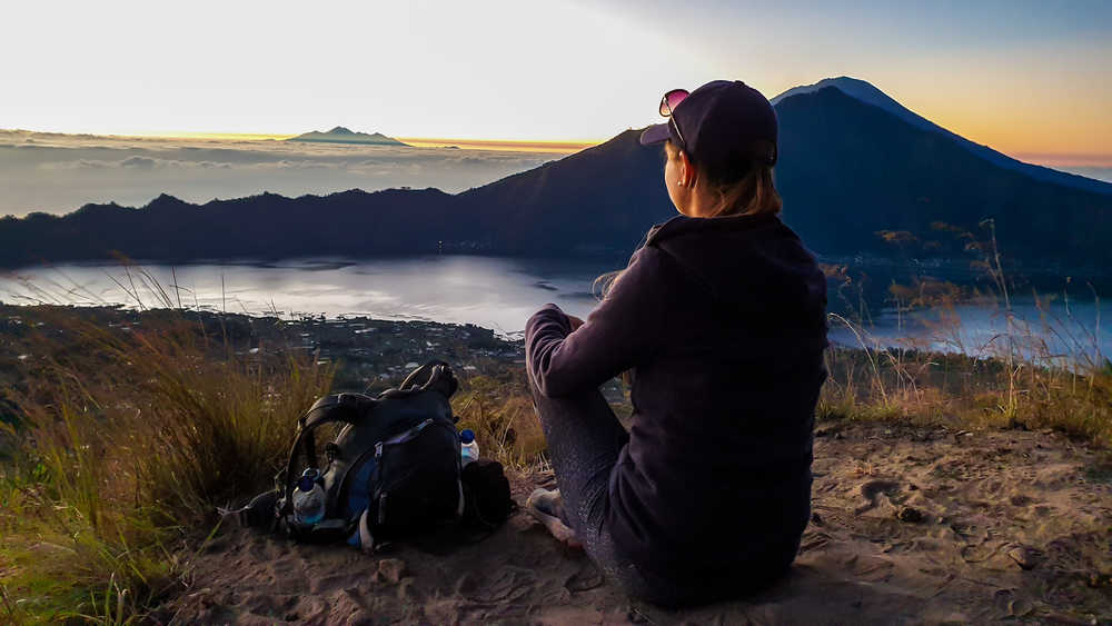 Jeune femme qui assiste au lever de soleil sur le Mont Batur en Indonésie