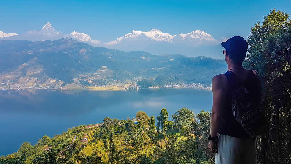 Jeune garçon de dos regardant les Annapurnas depuis le lac Phewa au Népal