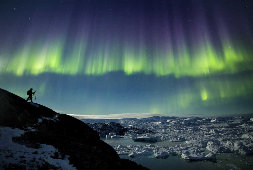 Photographe sous les aurores boréales au Groenland