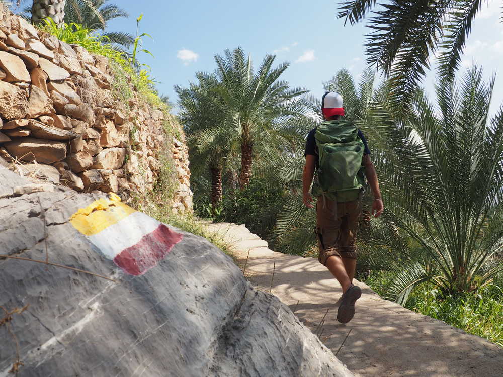 Randonneur de dos sur le sentier de la palmeraie à Misfat El Abreyeen au Sultanat d'Oman