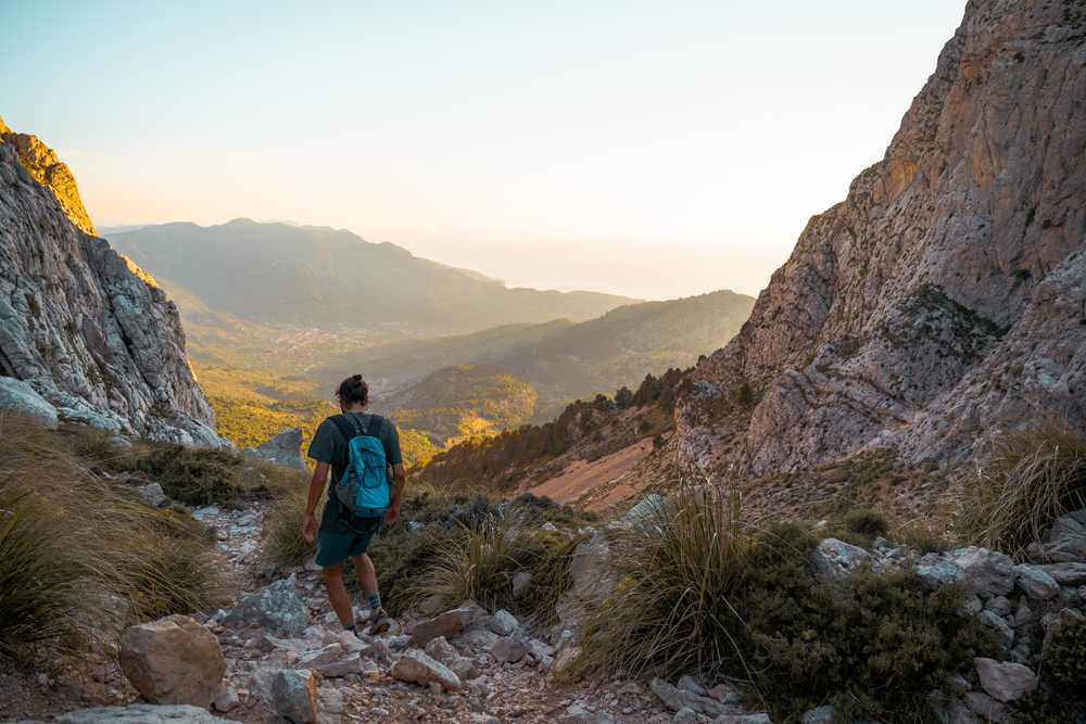 Randonneur marchant dans la Serra de Tramuntana au coucher de soleil, Majorque