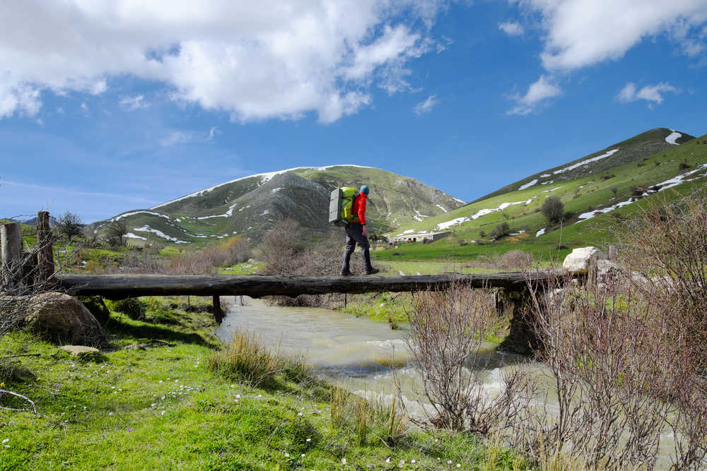 Randonneur traversant un pont au-dessus d'un ruisseau dans le parc de Nebrodi, en Sicile