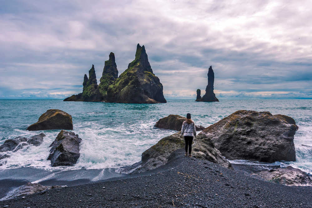 Randonneuse devant la plage de sable noir de Reynisdrangar, Islande