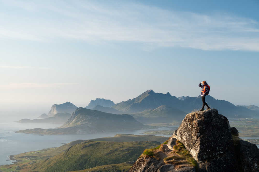 Randonneuse qui profite de la vue sur les montagnes et l'océan, Lofoten, Norvège