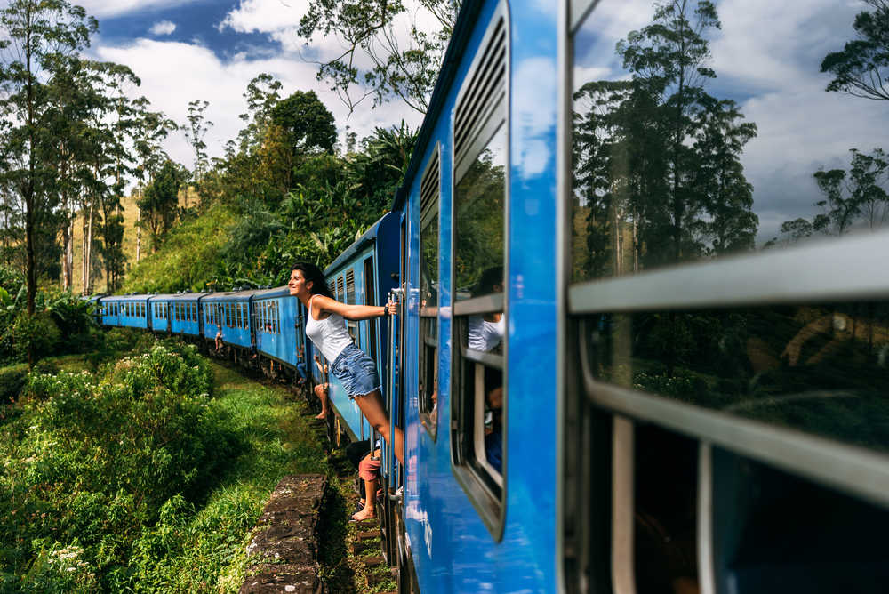 Train bleu Sri Lanka femme qui regarde par la porte du train