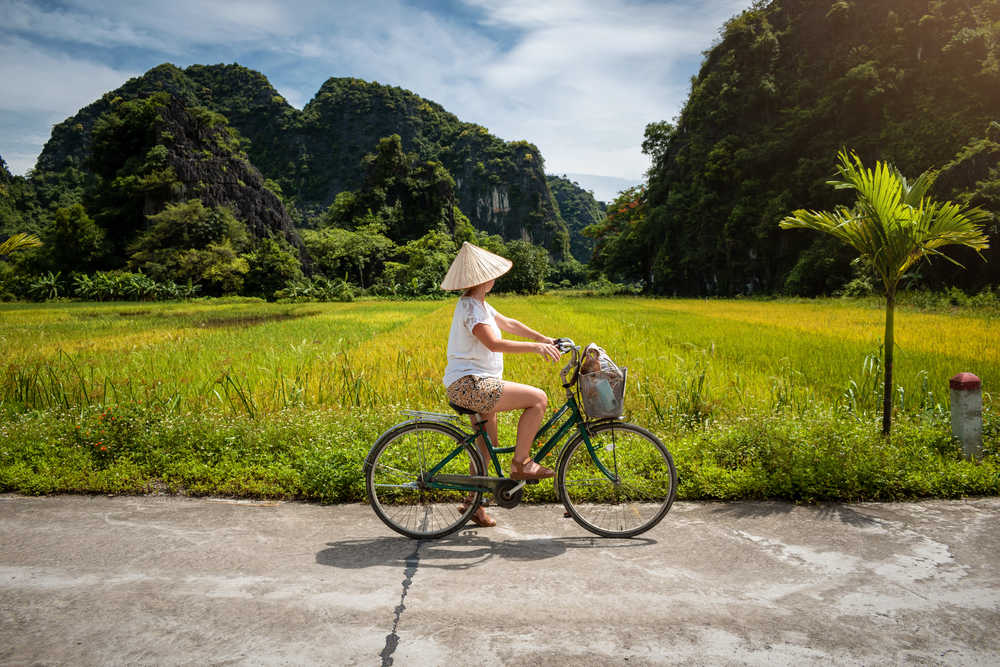 Une touriste à vélo se balade dans les rizières de Ninh Binh, Vietnam