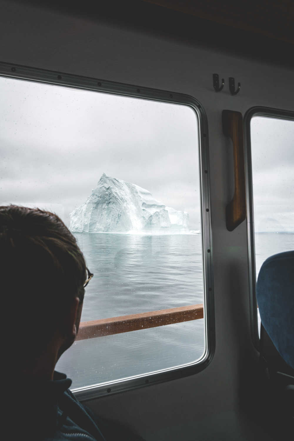 Voyageur qui regarde les icebergs de la fenêtre du bateau Groenland