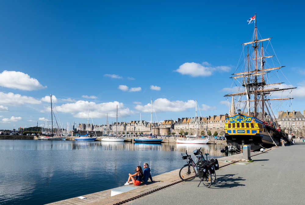 Cyclistes sur le port de Saint Malo avec le bateau l'étoile du roy en fond