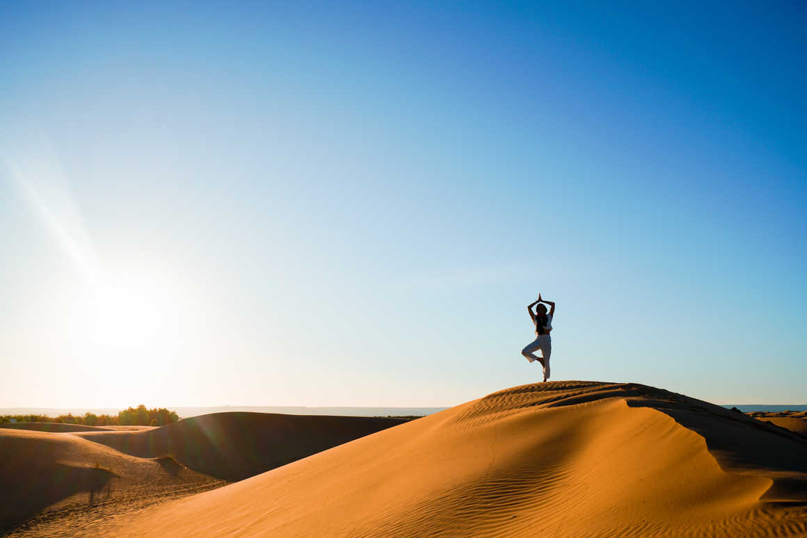 Femme faisant du yoga sur une dune de sable