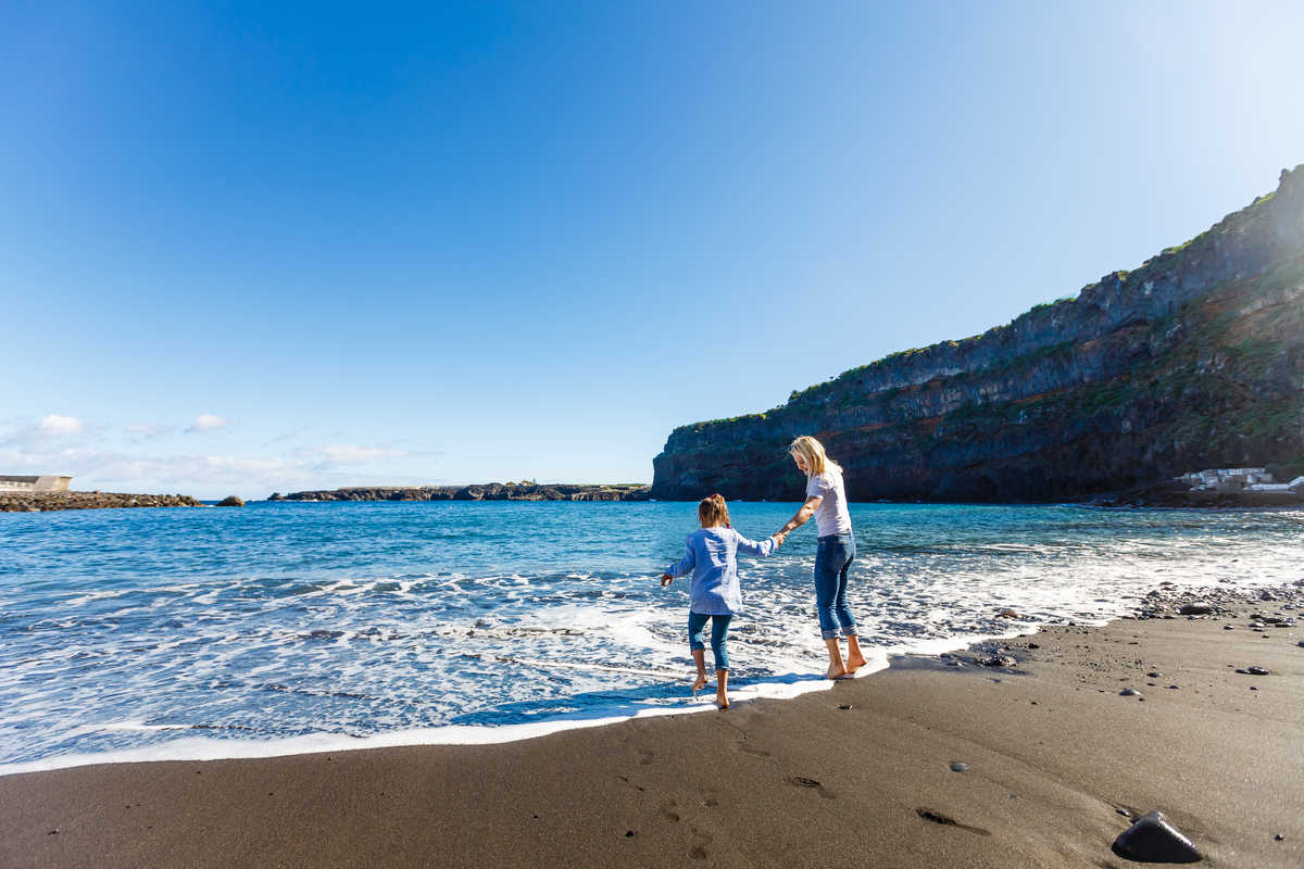 Enfant et sa mère au bord d'une plage de sable blanc