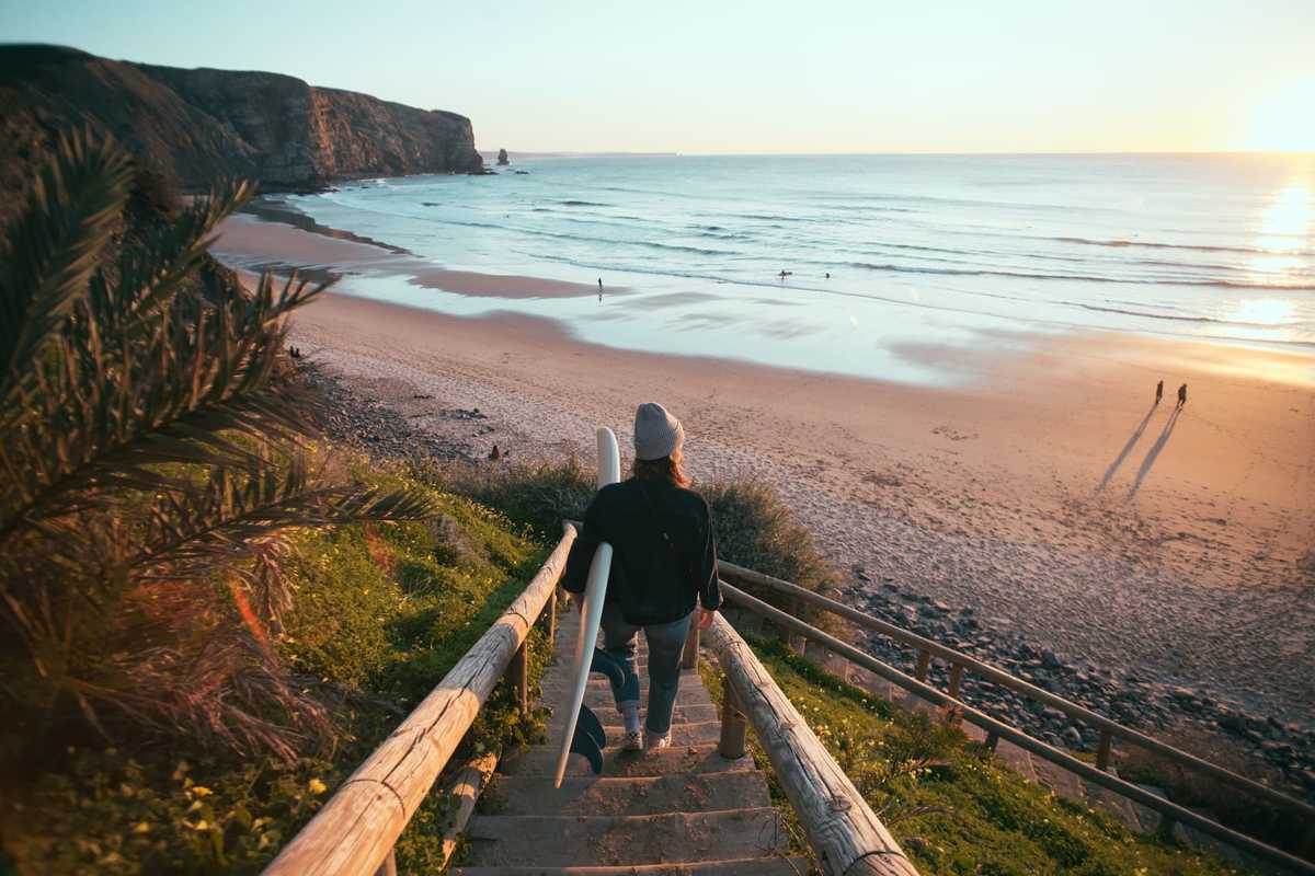 Plage, Algarve, Portugal © Adobe Stock Jeune femme sur la plage avec sa planche de surf à Algarve au Portugal