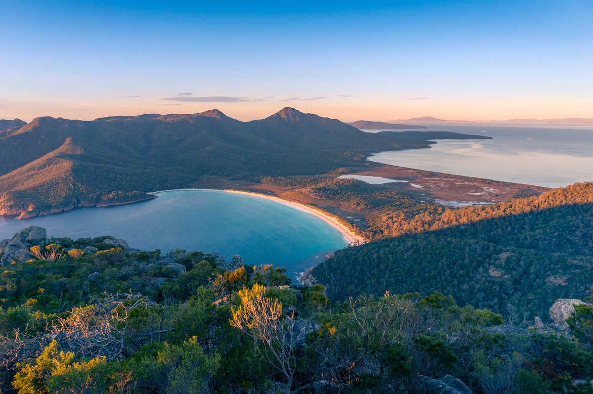 Lever de soleil sur une baie et des montagnes. Baie de Wineglass Tasmanie