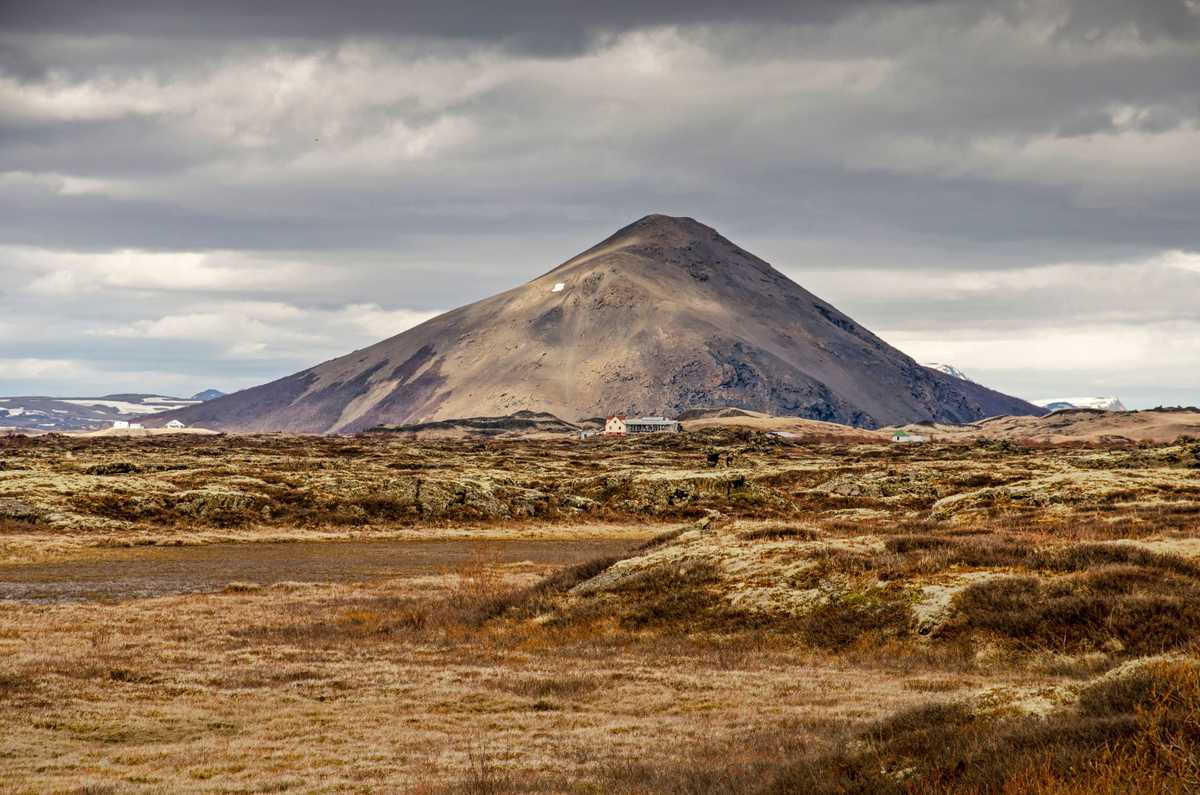 Vue sur un paysage de mousse, d'herbe, d'arbustes et de fermes dispersées en direction du mont Vindbelgjarfall dans la région de Myvatn en Islande.