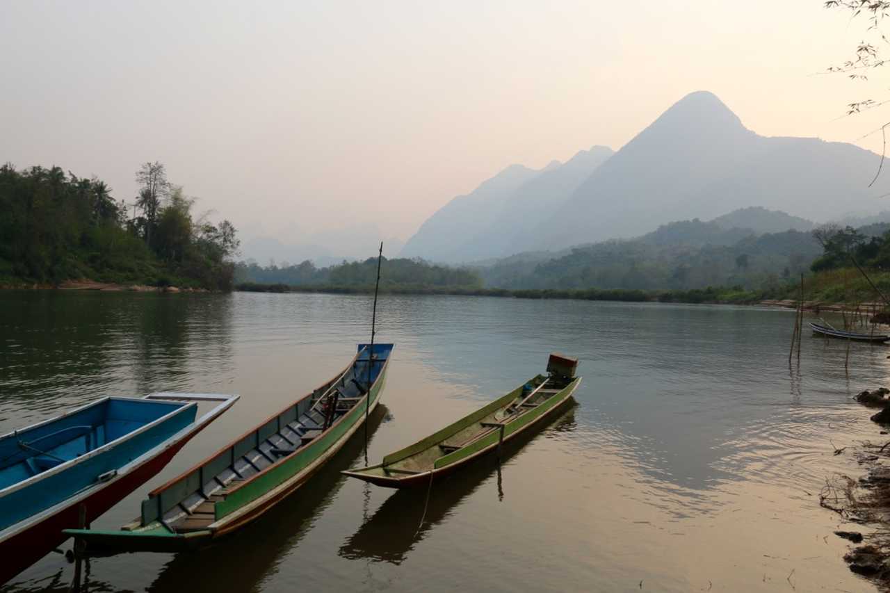 couchée de soleil avec des barques dans un lac au Laos