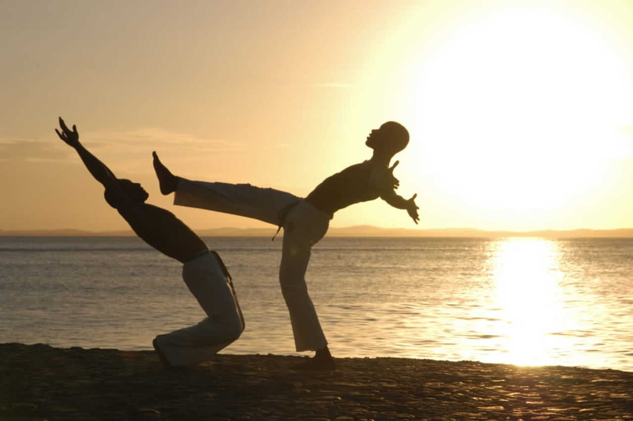 Deux jeunes-hommes faisant de la capoeira sur la plage au Brésil