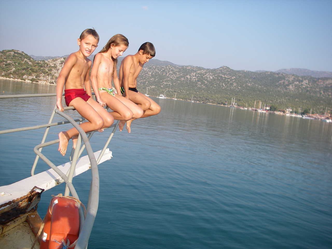 Enfants assis sur le pont avant d'un bateau au milieu de la mer
