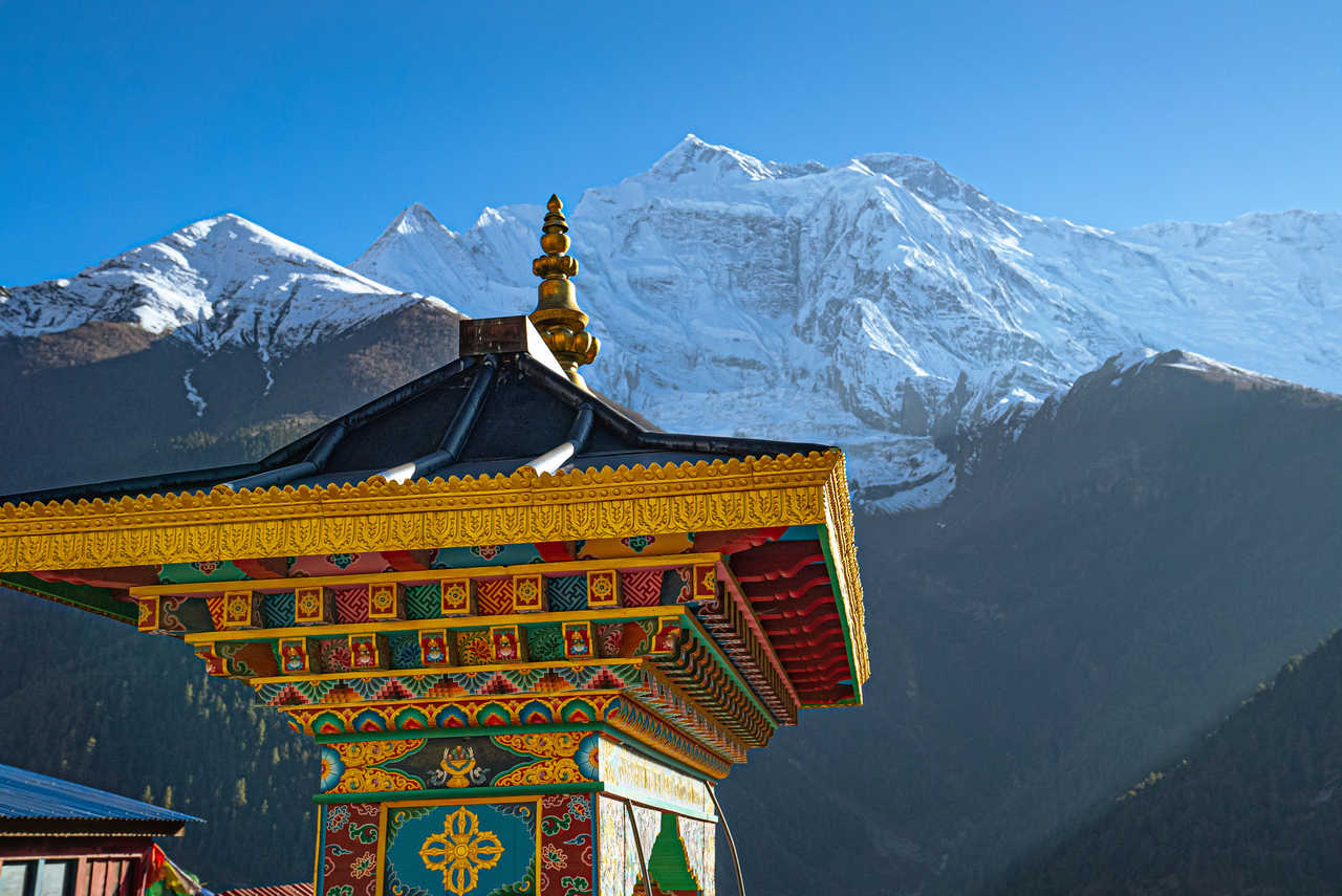 Entrée d'un temple coloré avec la chaîne de l'Annapurna au loin, Népal