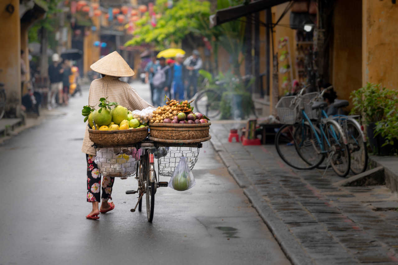 Femme marchant à Hoi An avec des fruits au Vietnam