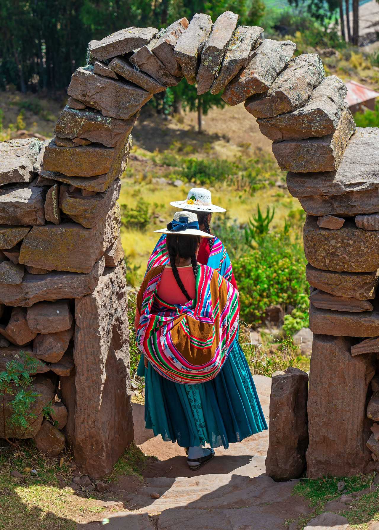 Femmes en tenue traditionnelle sous une arche de pierre sur l'île de Taquile, Lac Titicaca