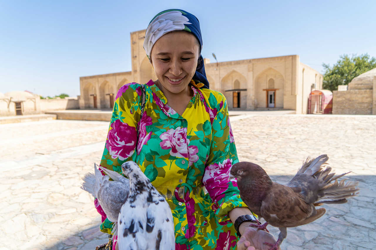 Fille avec des colombes sur fond de ville ancienne. Boukhara, Ouzbékistan