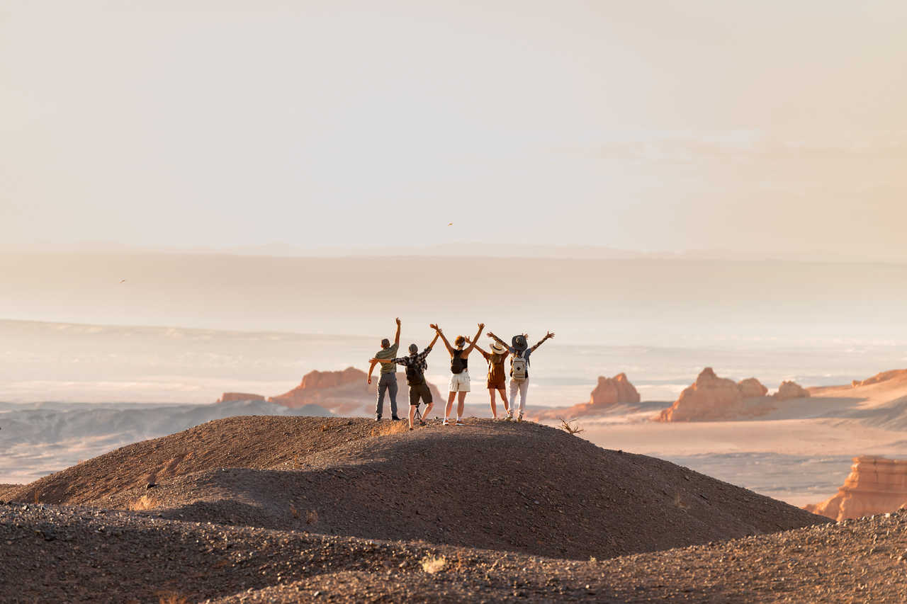 Groupe de randonneurs heureux qui se tiennent bras ouverts devant un point de vue dans un désert de Mongolie
