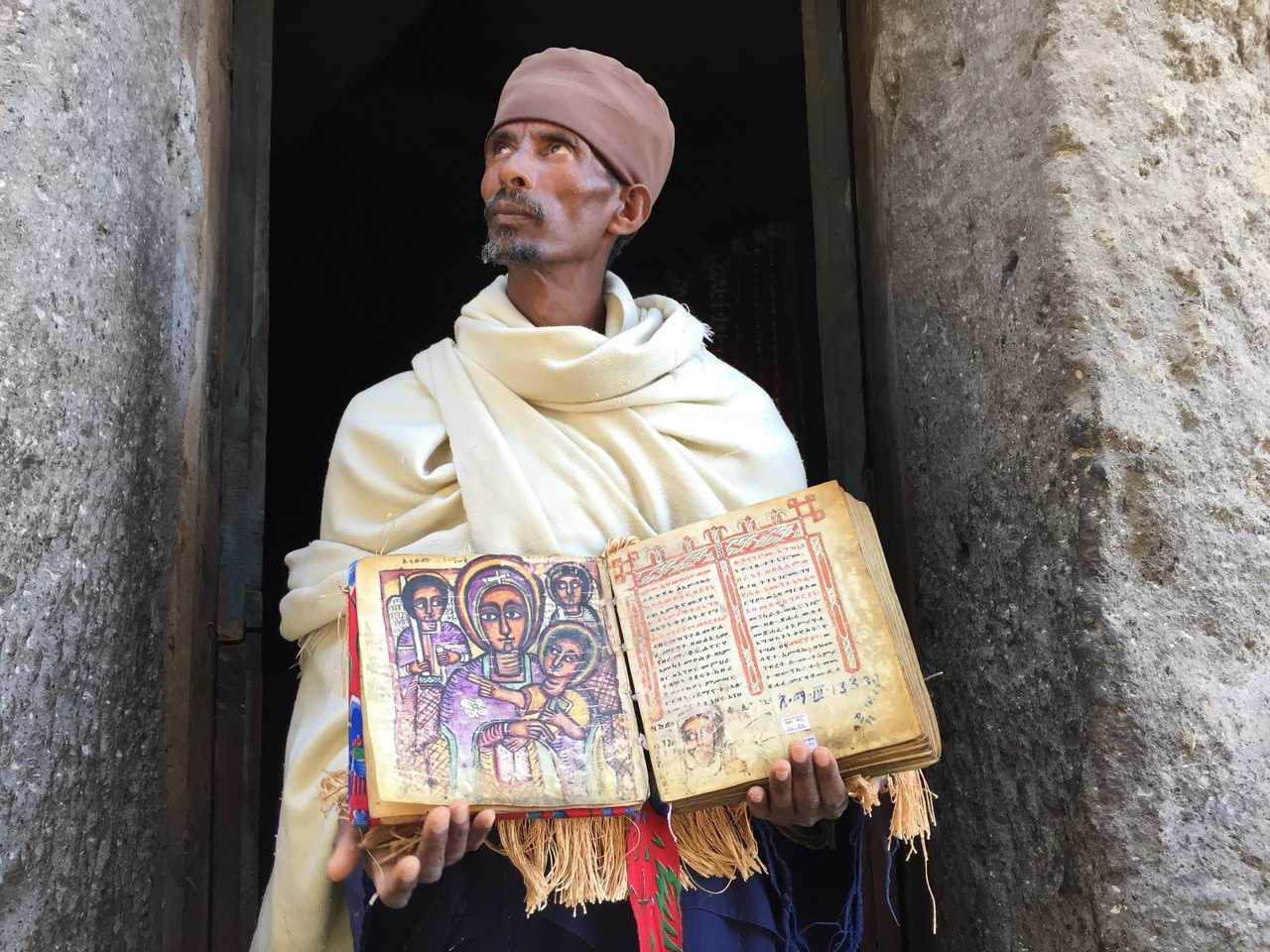 Homme d'église tenant un livre sacré sur les hauts plateaux éthiopiens