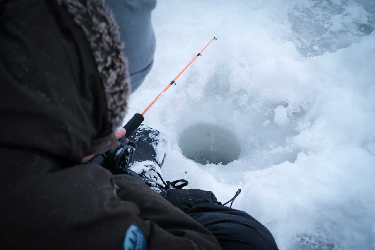 Homme qui pêche dans un lac glacé en Finlande