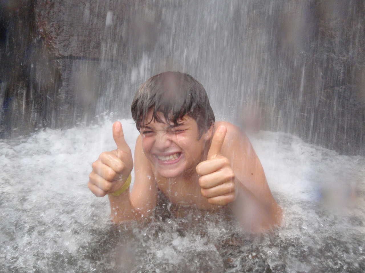 Jeune adolescent rigolant sous une cascade au Sri Lanka
