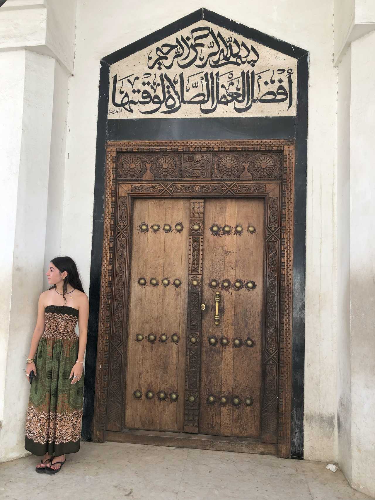 Jeune fille devant une porte stylisée à Zanzibar