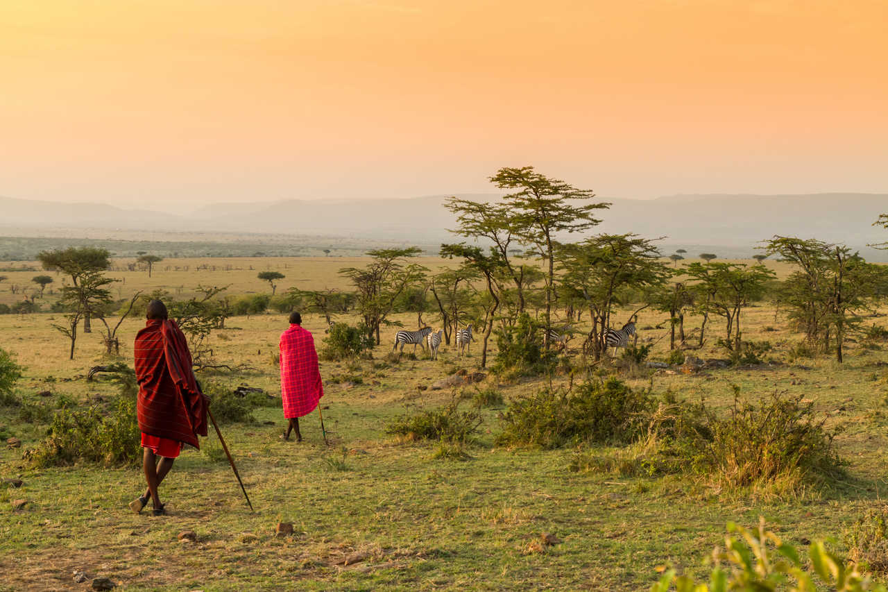 Masai marchant dans la brousse au coucher de soleil au Kenya