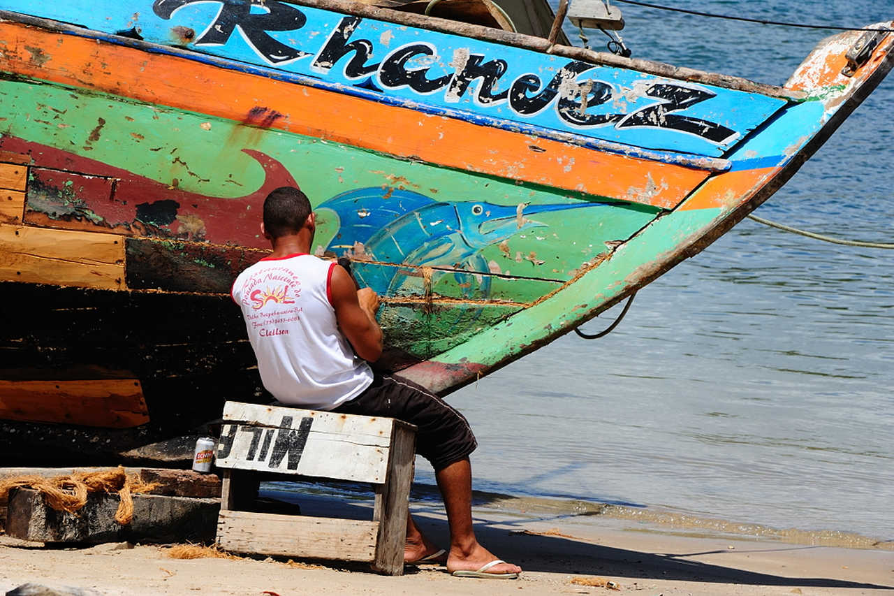 Pêcheurs en train de réparer son bateau sur une plage au Brésil