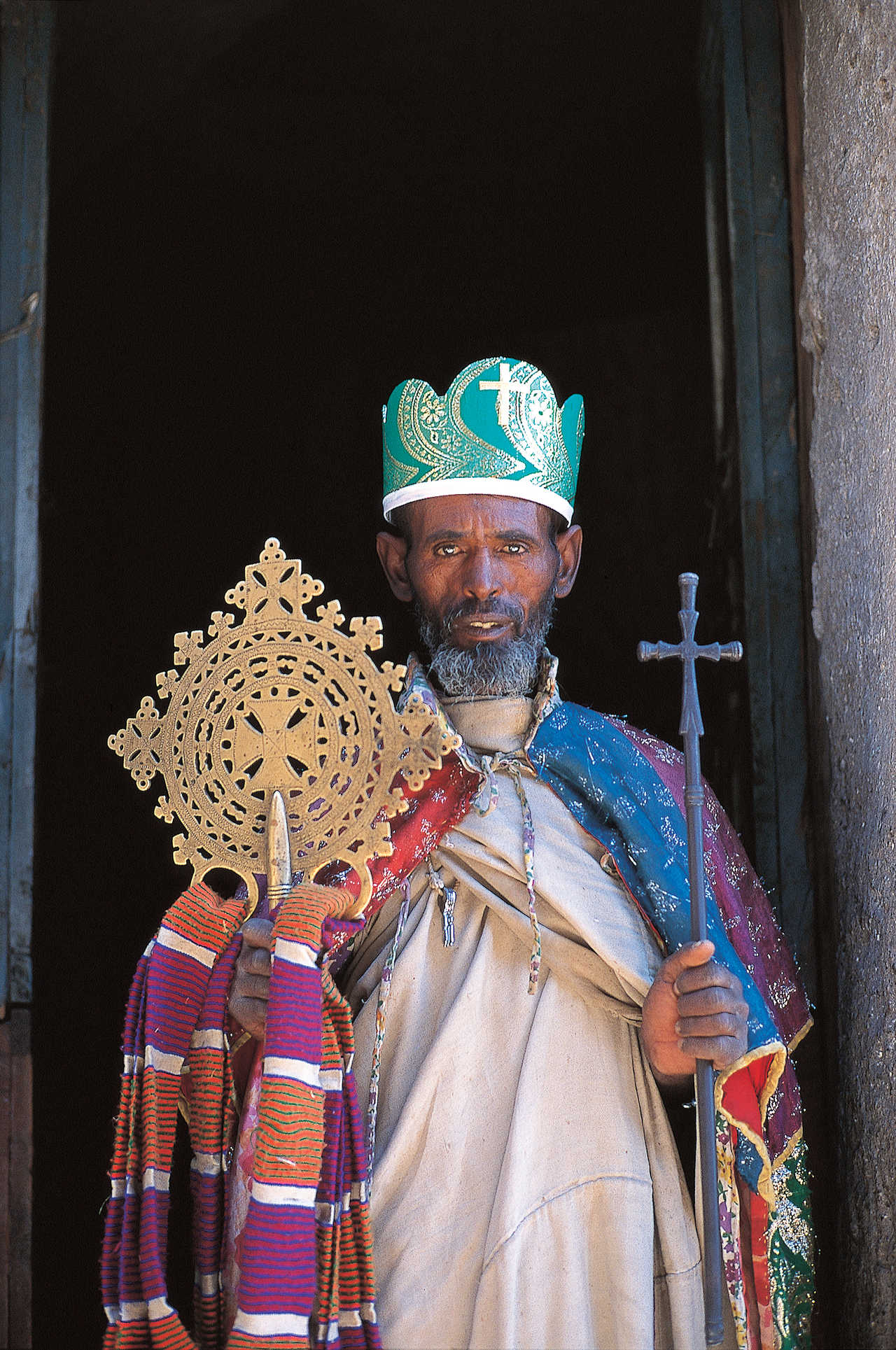 Prêtre éthiopien tenant les croix sacrées devant une église