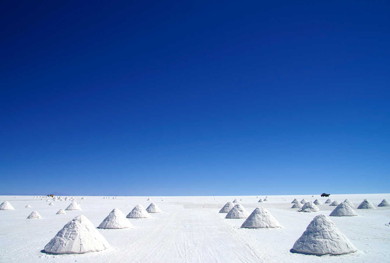 Pyramides de sel blanc séchant sous un ciel bleu intense dans le Salar d'Uyuni, étape emblématique du voyage en Bolivie.