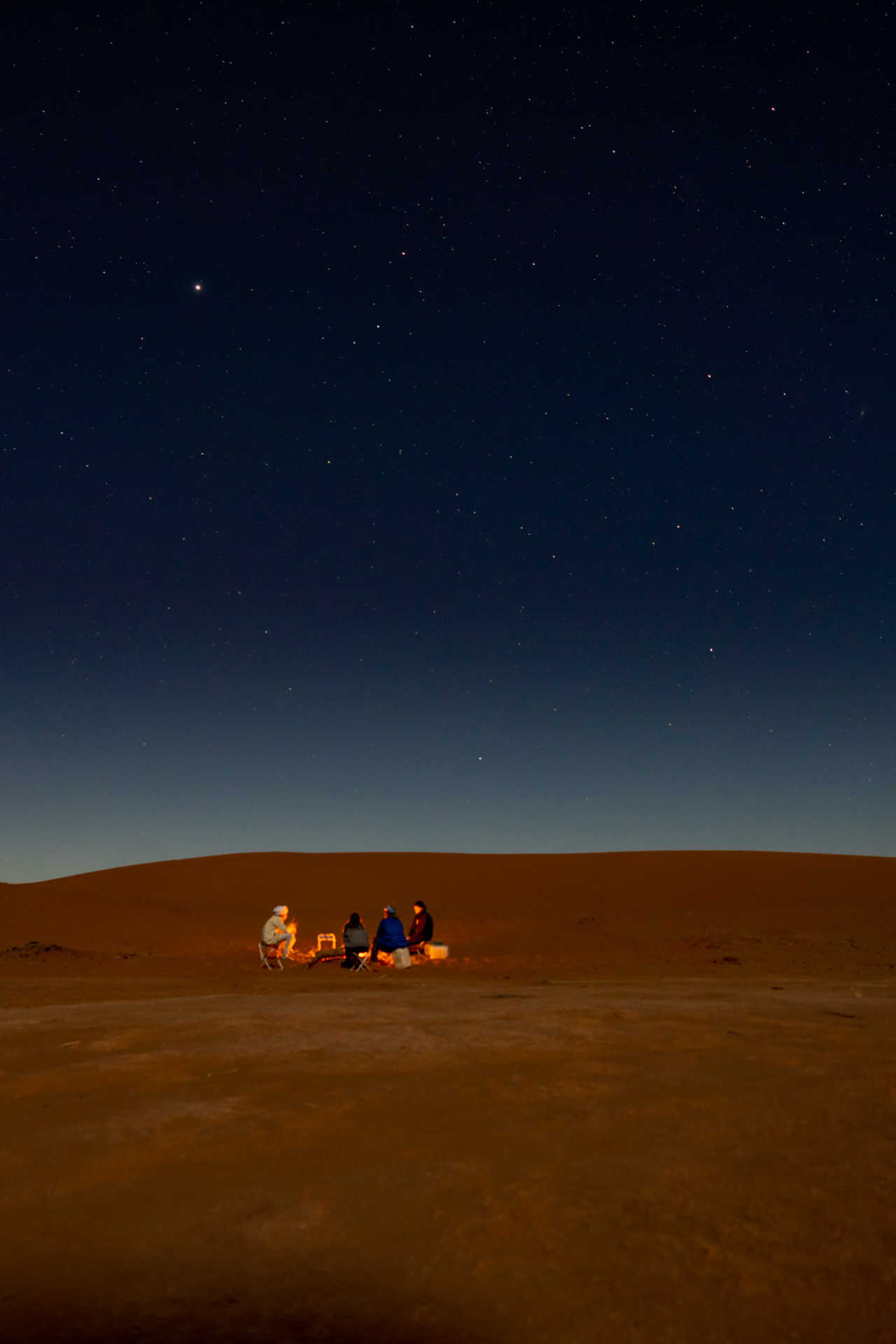 Randonneurs autour du feu de camp dans le désert marocain de nuit