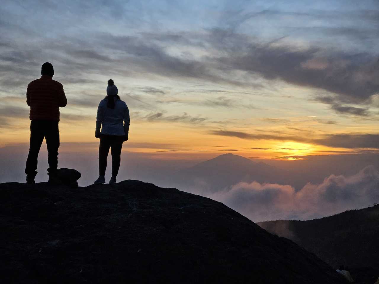 Randonneurs qui admirent la vue au coucher de soleil pendant l'ascension du Kilimandjaro en Tanzanie