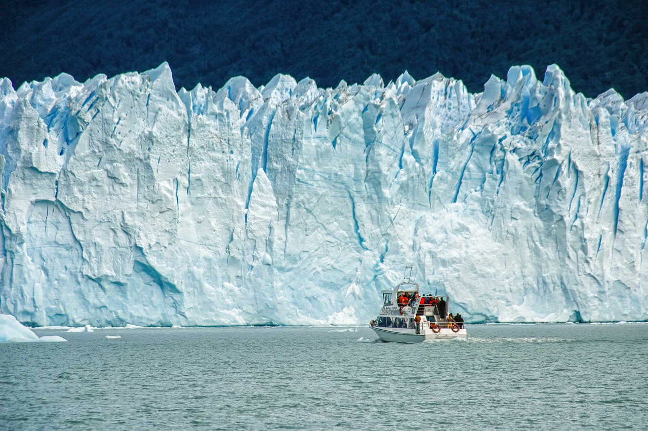 Un bateau d'excursion navigue sur les eaux du lac Argentino, s'approchant au plus près de l'immense mur de glace bleue du glacier Perito Moreno en Patagonie argentine