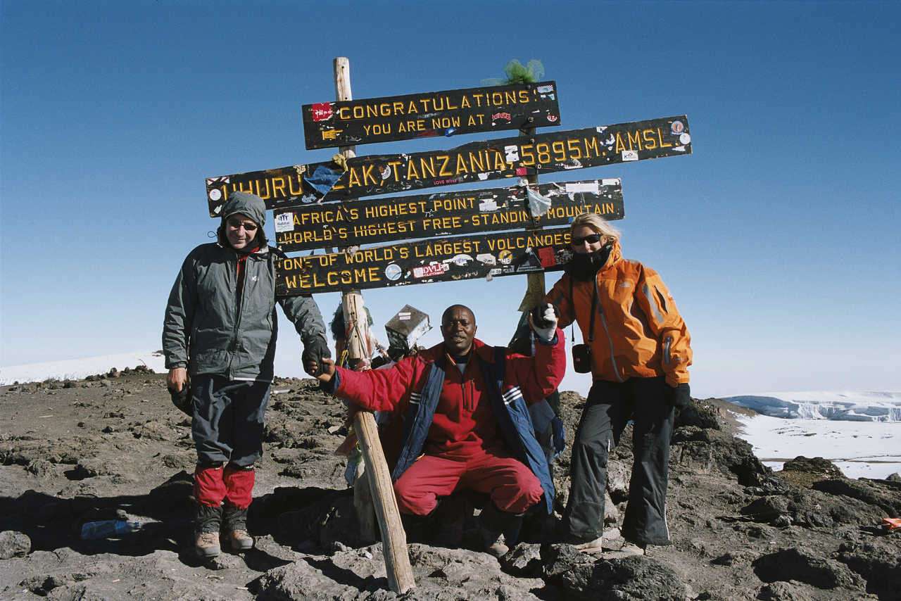 Un couple au sommet du Kilimandjaro accompagné de leur guide en Tanzanie