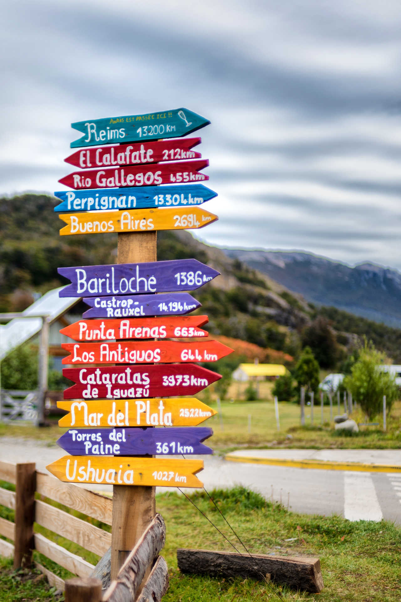 Un panneau directionnel en bois aux flèches colorées indiquant les distances vers diverses destinations comme Ushuaia ou El Calafate, photographié dans le village d'El Chaltén en Patagonie argentine.