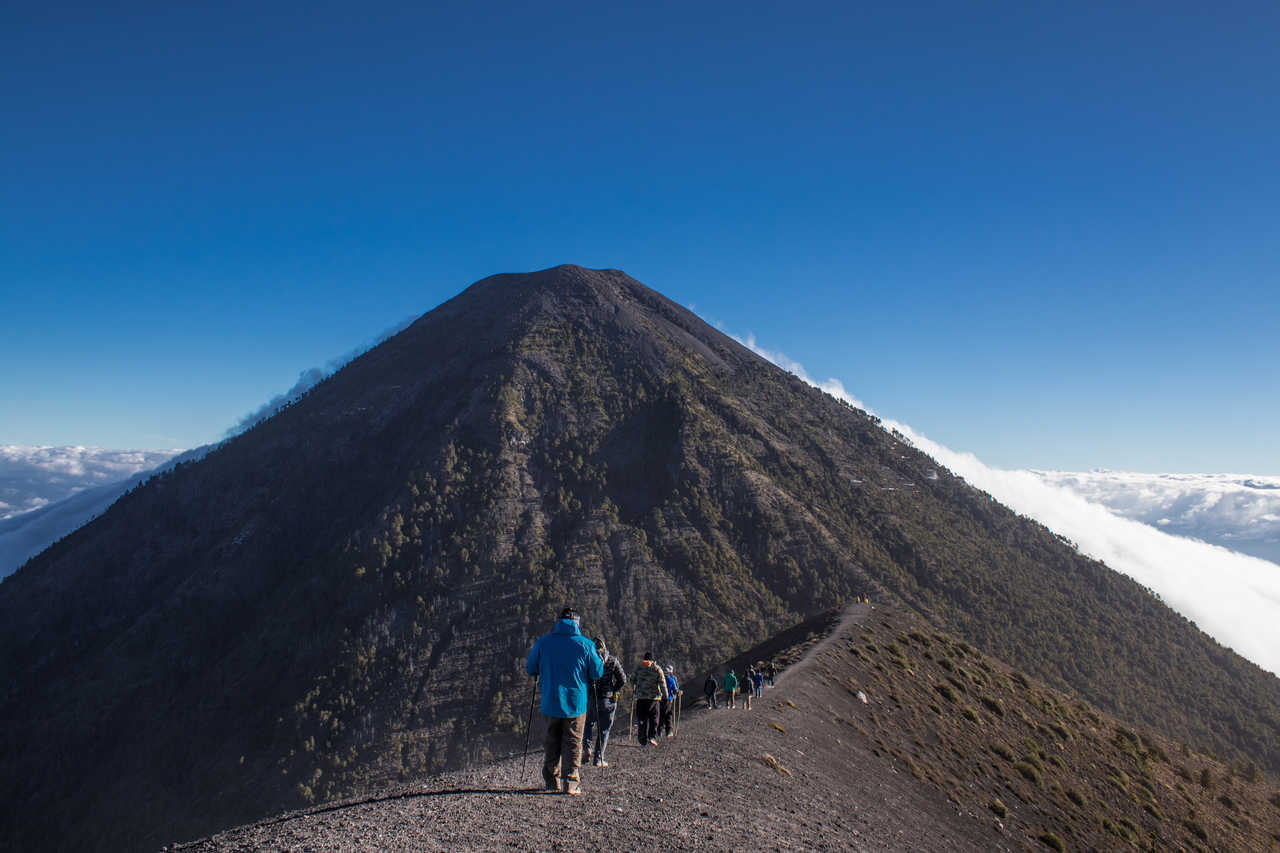 Vue d'ensemble d'un groupe de randonneurs marchant en file indienne sur le sentier, avec vue sur le volcan Acatenangoau Guatemala