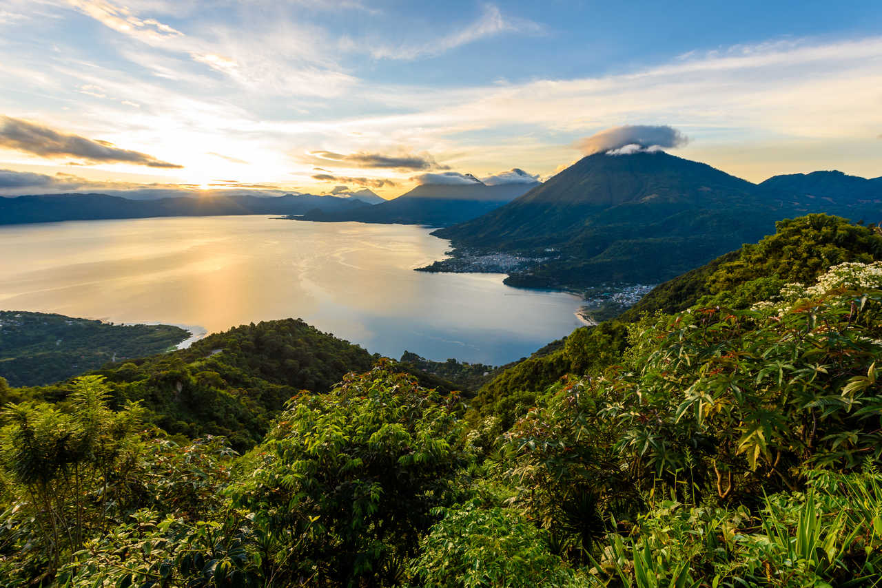 Vue plongeante sur les eaux bleues du lac Atitlán entouré des volcans San Pedro, Toliman et Atitlán au Guatemala